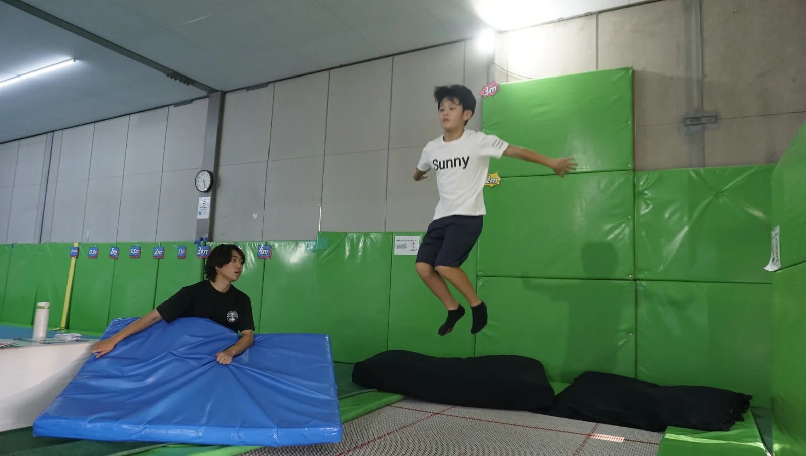 マットに向かって高くジャンプする男の子